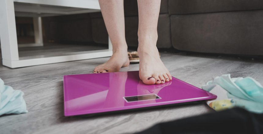 conceptual image about insecurities in women about weigh and eating disorders with a woman feet and a pink scale