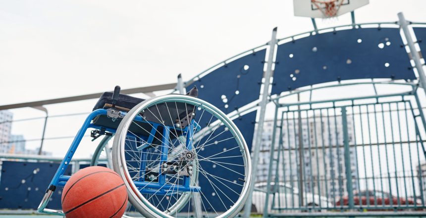 Image of empty wheelchair with basketball ball on the outdoor sport ground